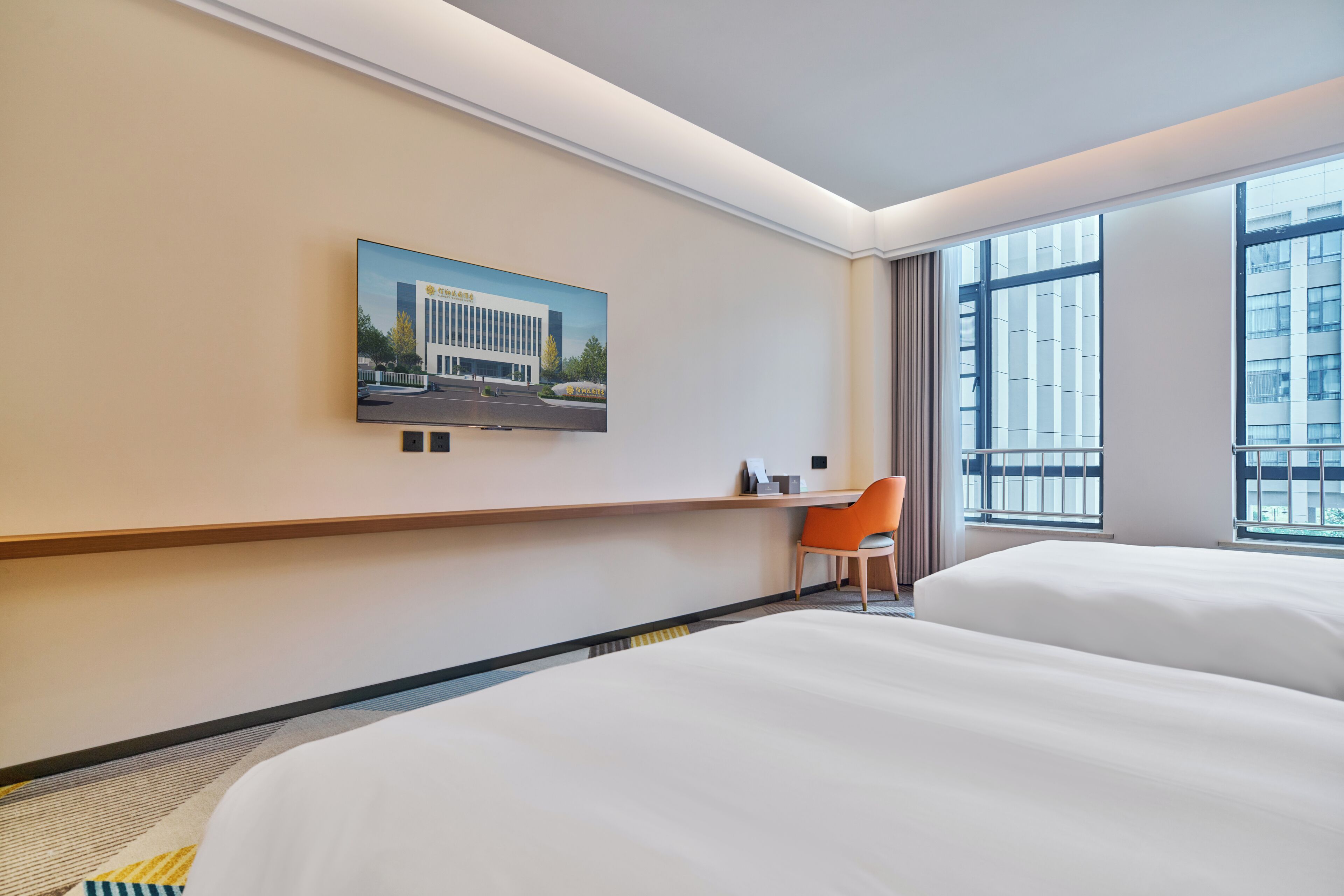Habitación de hotel con una cama grande, un escritorio, una silla, un ventanal con vistas a edificios y un cuadro en la pared.