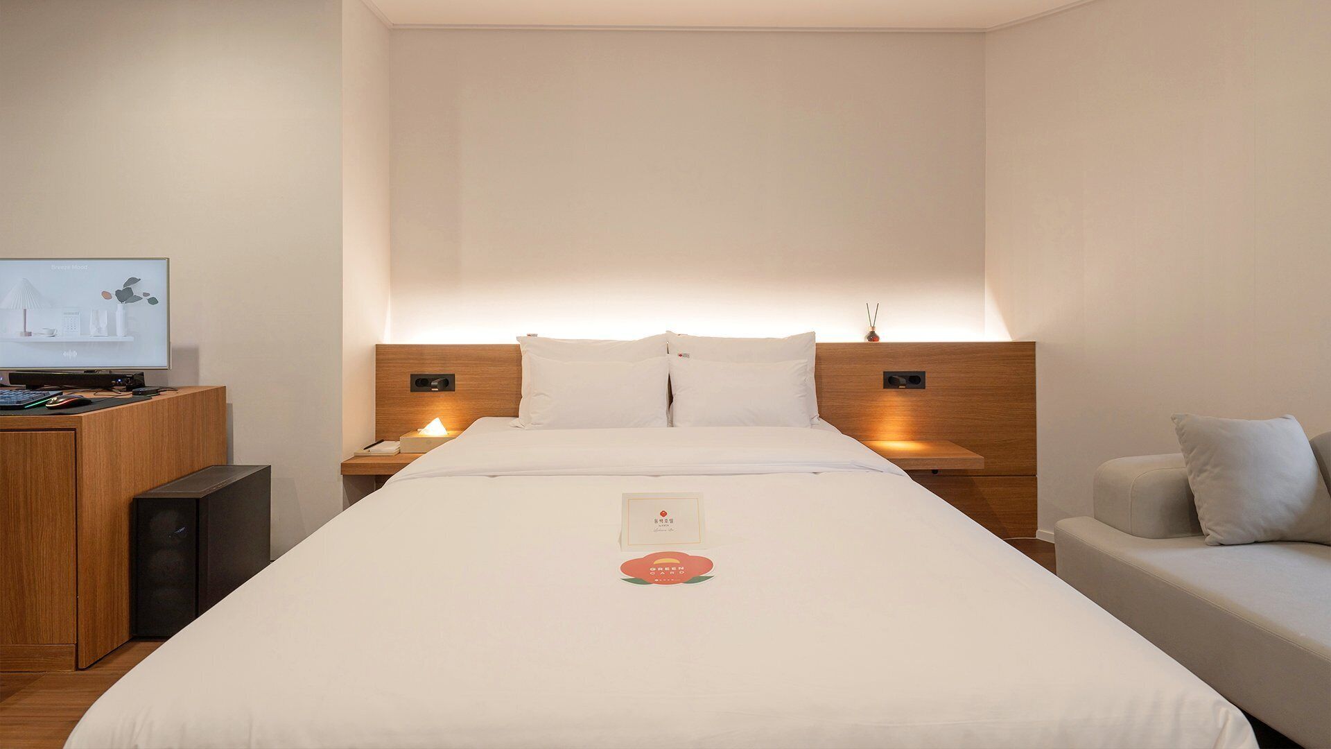 Habitación de hotel con cama, mesitas de noche, escritorio con computadora y televisión.