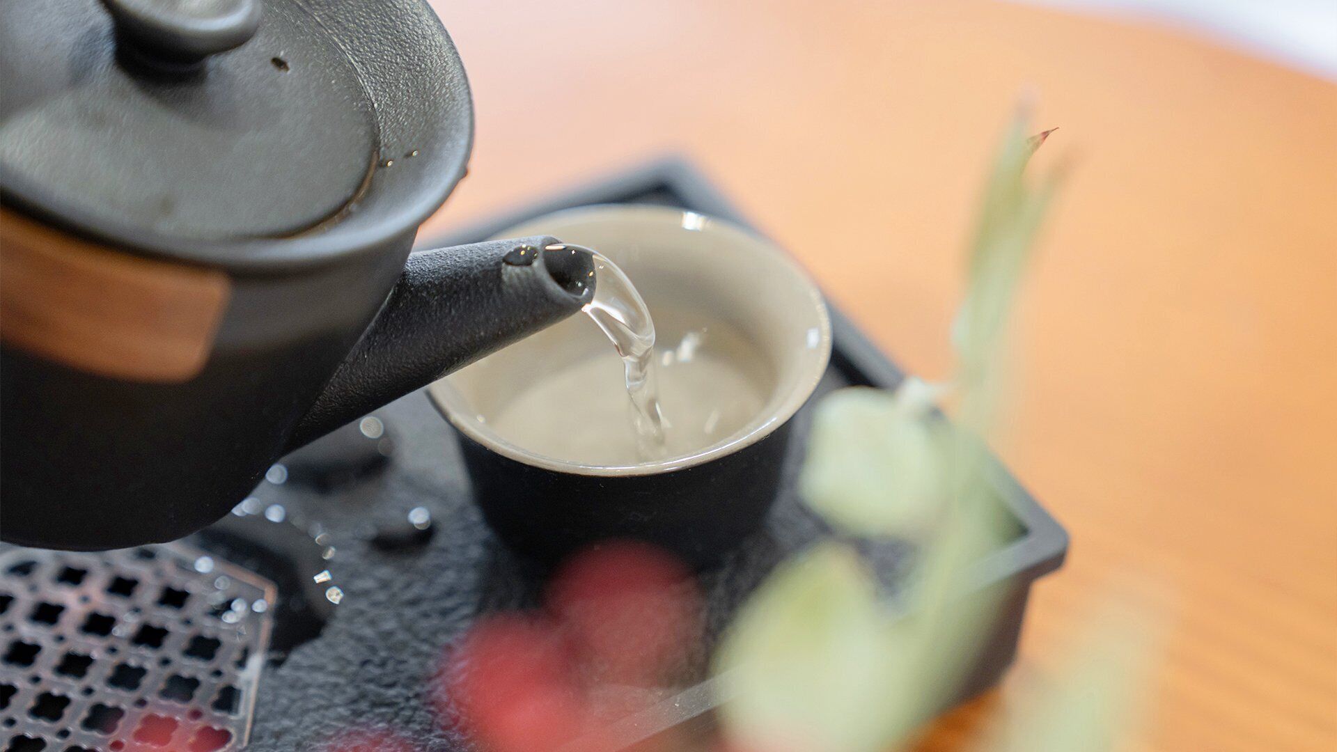 A teapot pouring water into a cup.