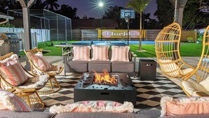 Eine Terrassengaststätte mit Feuerstelle, Sitzgelegenheiten und einem Pool im Hintergrund.
