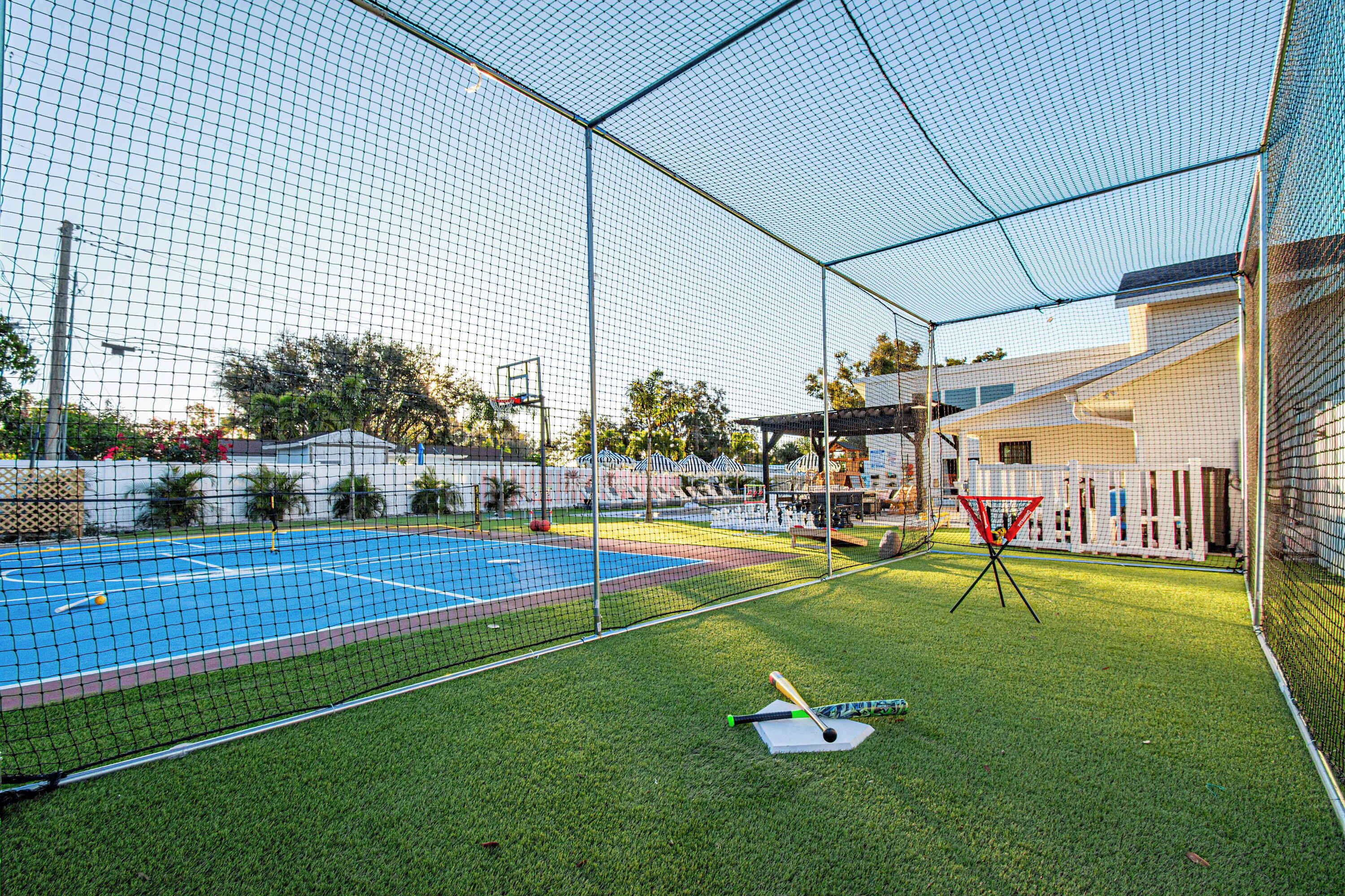 En sportsbane med net, en basketballkurv og et bur til baseball.