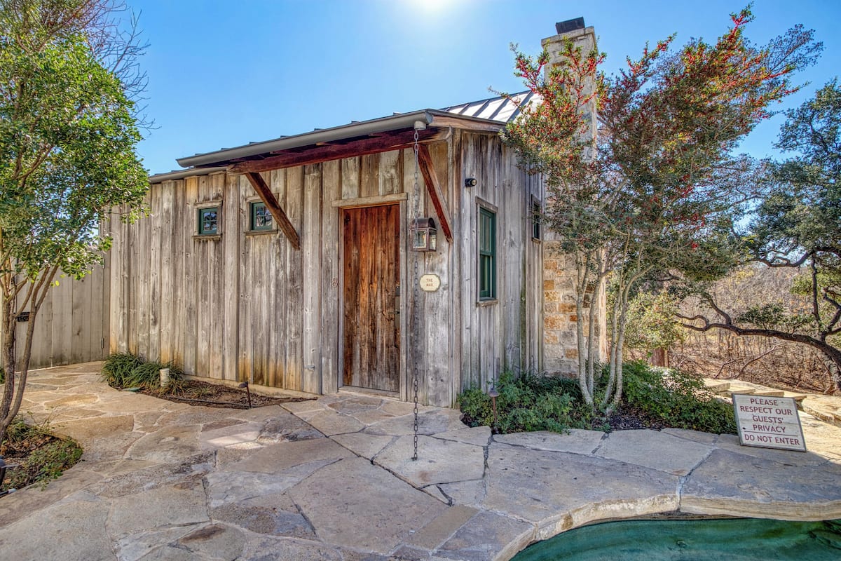 A rustic wooden building with a stone pathway leading to a wooden door.