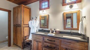A wooden vanity with a sink, two mirrors, and a towel rack.