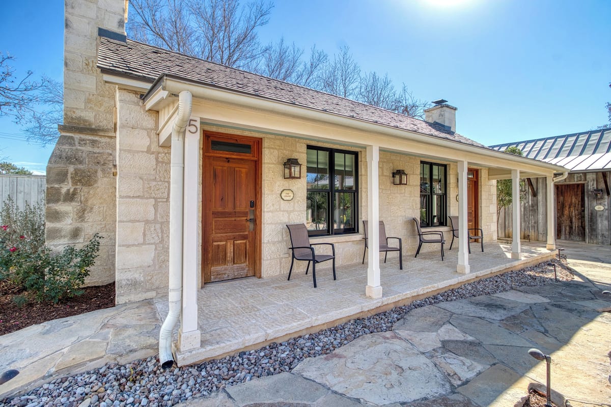 A stone building with a covered porch, stone steps, and outdoor seating.
