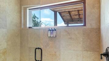 Una ducha con techo de madera, ventana y suelo de baldosas.