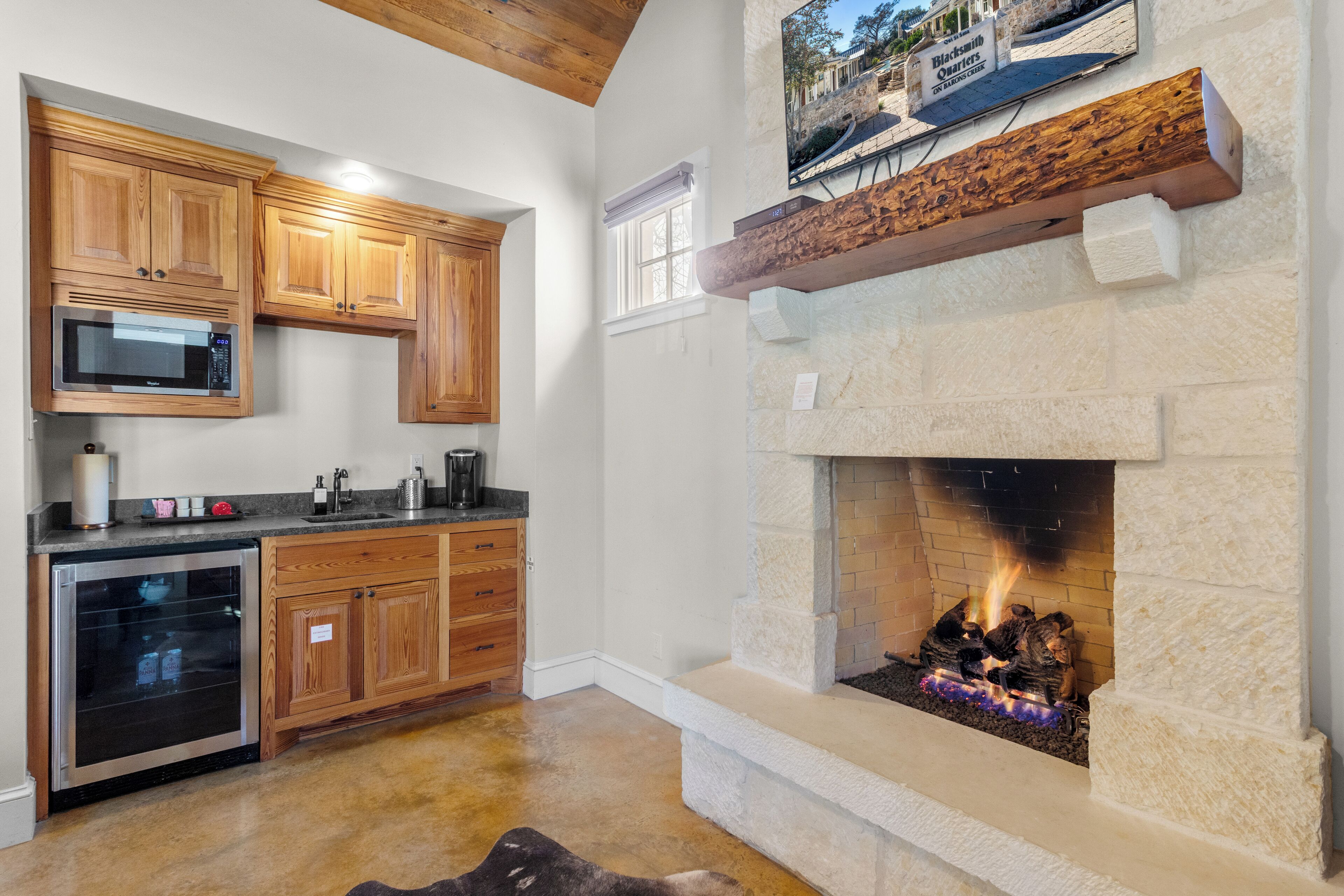Eine Küche mit Holzausstattung, einer Mikrowelle, einem Backofen und einem Kamin aus Stein mit Feuer.