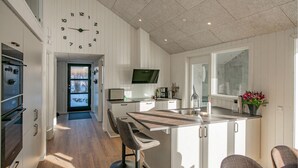 Eine moderne Küche mit einer zentralen Kochinsel, Barhocker und einem großen Fenster.