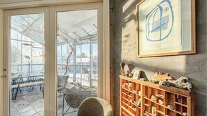 A conservatory with a glass door leading to an outdoor seating area.
