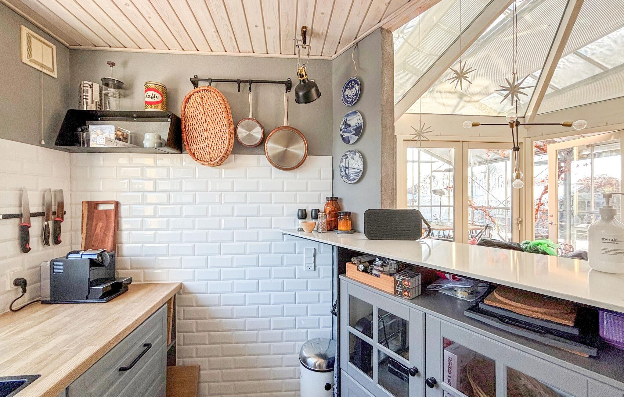 Une cuisine de taille réduite avec des murs en briques blanches, un plan de travail en bois et une fenêtre donnant sur l’extérieur.