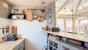 A compact kitchen with white brick walls, a wooden countertop, and a window with a view of the outside.