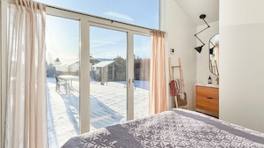 A bedroom with a large sliding glass door leading to a snowy outdoor area.