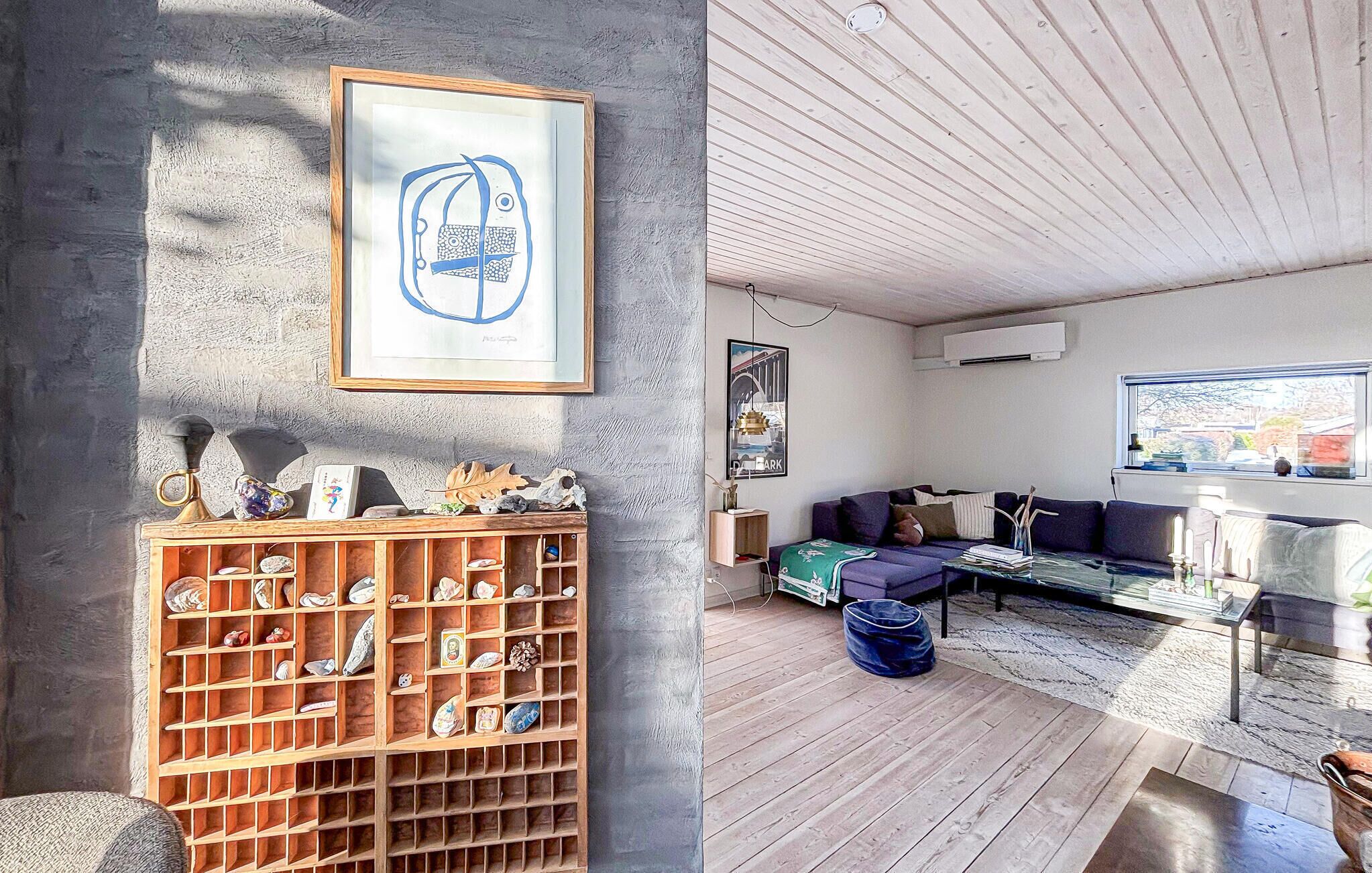Een moderne woonkamer met een houten vloer, een bank, een salontafel en een wandplank met decoratieve objecten.