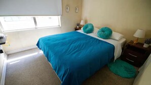 A bedroom with a large bed, a nightstand, a lamp, and a window. - Central and comfortable apartment in Santiago Centro. (Santiago)