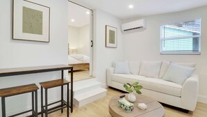Una sala de estar moderna con un sofá, una mesa de centro y una escalera que conduce a un dormitorio.