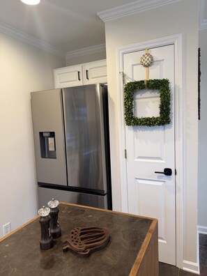 A kitchen with a stainless steel refrigerator, a wooden countertop, and a white door with a green wreath. - Acorn Cottage a Peaceful 3-bedroom house 1 mile from Elon University (Elon)