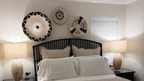 Un dormitorio con una cama, dos mesitas de noche y un ventilador de techo.