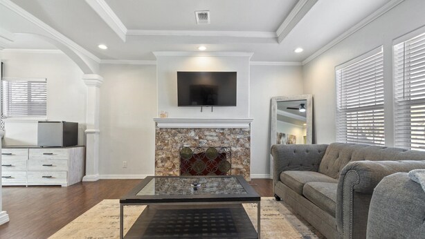 A living room with a fireplace, a flat-screen TV mounted above it, a sofa, and a coffee table. - 3-bedroom house in central San Antonio with AC for comfort (San Antonio)