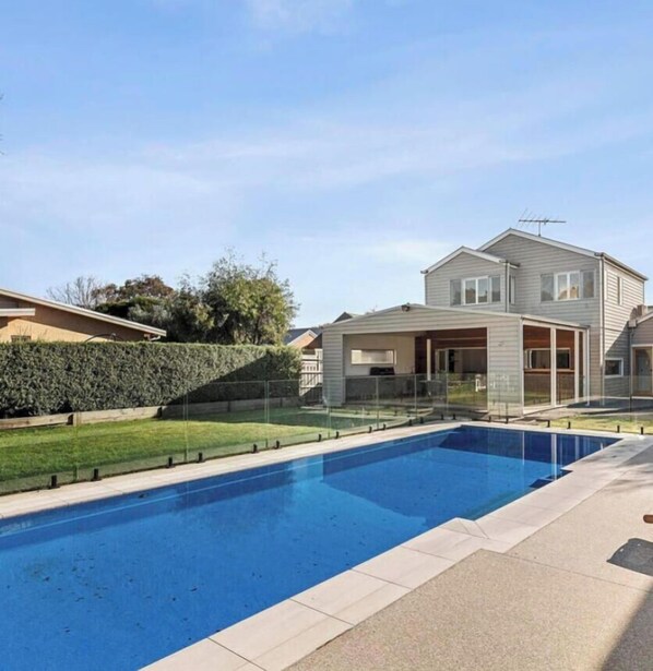 A residential swimming pool with a clear blue water surface, surrounded by a tiled deck. - Pool House Barwon Heads 4 bedroom, 2 bathroom, sleeping 8, Heated Pool (Barwon Heads)