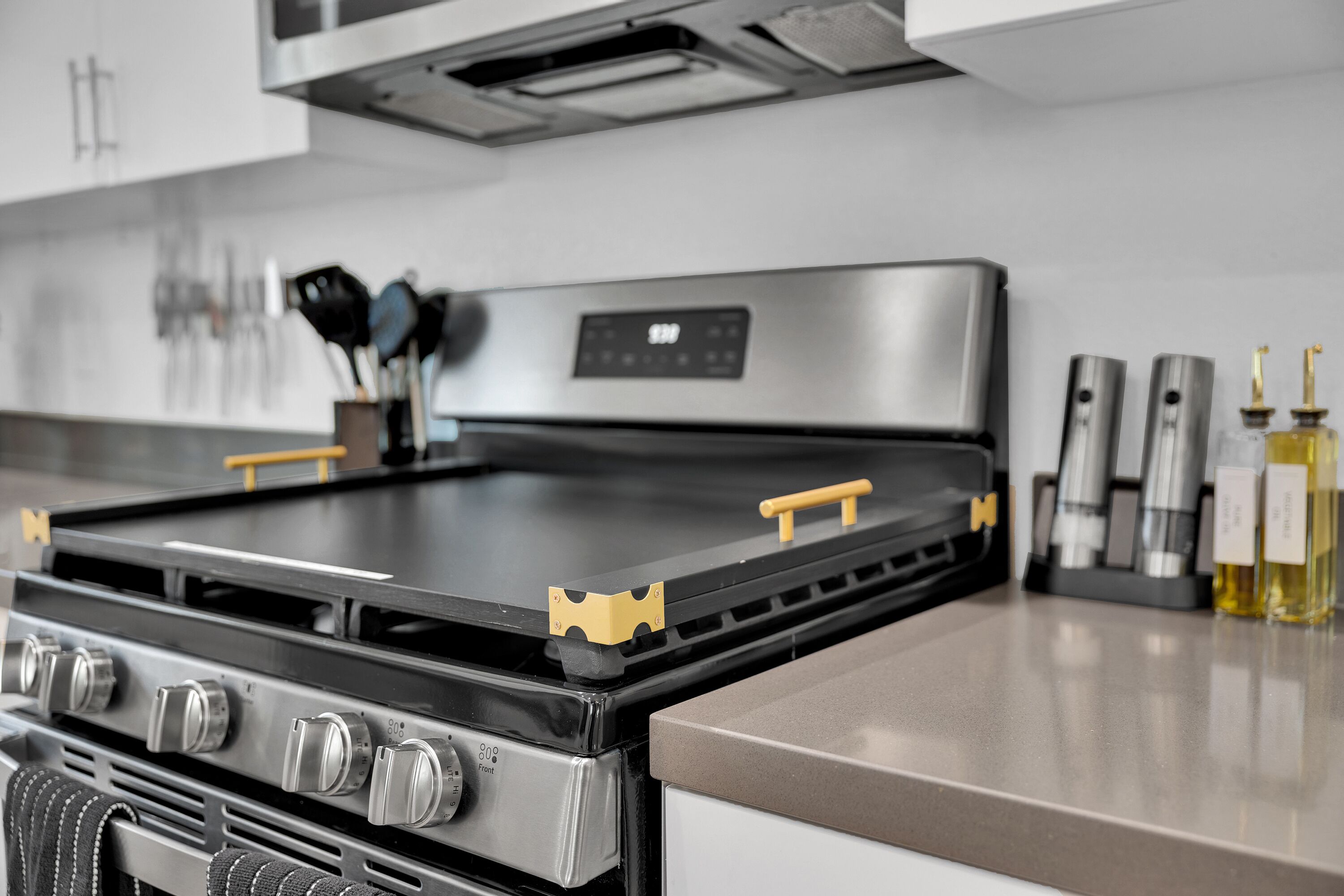 A kitchen with a stainless steel stove, a range hood, and a set of knives on the wall.