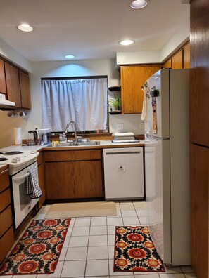 A compact kitchen with wooden cabinets, a white refrigerator, a sink, and a stove. - Garden Sanctuary, Mid-term, Peaceful Lake-town Home (Lake Stevens)
