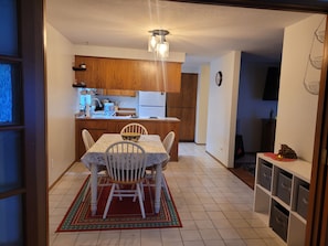 A compact kitchen with wooden cabinets, a dining table with chairs, and a rug. - Garden Sanctuary, Mid-term, Peaceful Lake-town Home (Lake Stevens)