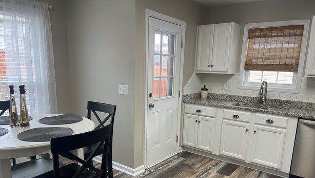 A kitchen with white cabinets, a granite countertop, and a wooden floor. - Cozy home in Opelika/Easy interstate access/Short drive to downtown and Auburn. (Opelika)