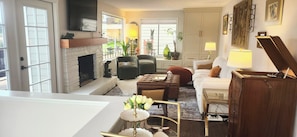 A living room with a fireplace, seating area, and a view of the outdoors.