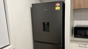 Eine Küche mit einem schwarzen Kühlschrank, weißen Schränken und einer Mikrowelle.