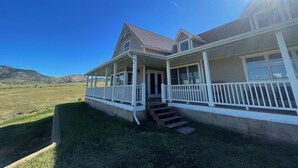 A two-story house with a covered porch and a front entrance. - Large Group Lodge with Breathtaking Montana Views (cardwell)