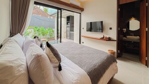 Een moderne slaapkamer met een groot bed, een aan de muur bevestigde televisie en een badkamer met een wastafel en spiegel.