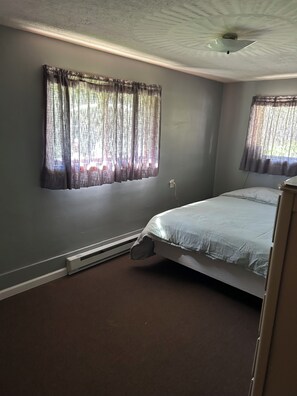 A room with a bed, a heater, a window with curtains, and a ceiling fan. - Cozy connection near downtown Warren (Warren)