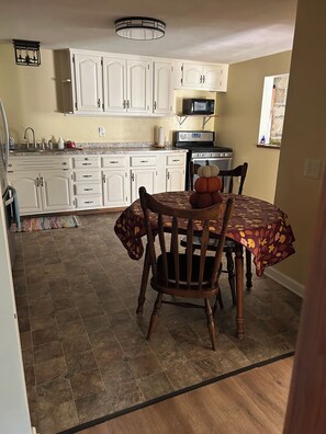 A dining area with a table set for two, a kitchen in the background, and a rug leading to the dining space. - Cozy connection near downtown Warren (Warren)