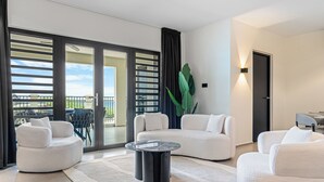 Ein modernes Wohnzimmer mit einem weißen Sofa, einem runden Couchtisch und einer großen Pflanze.