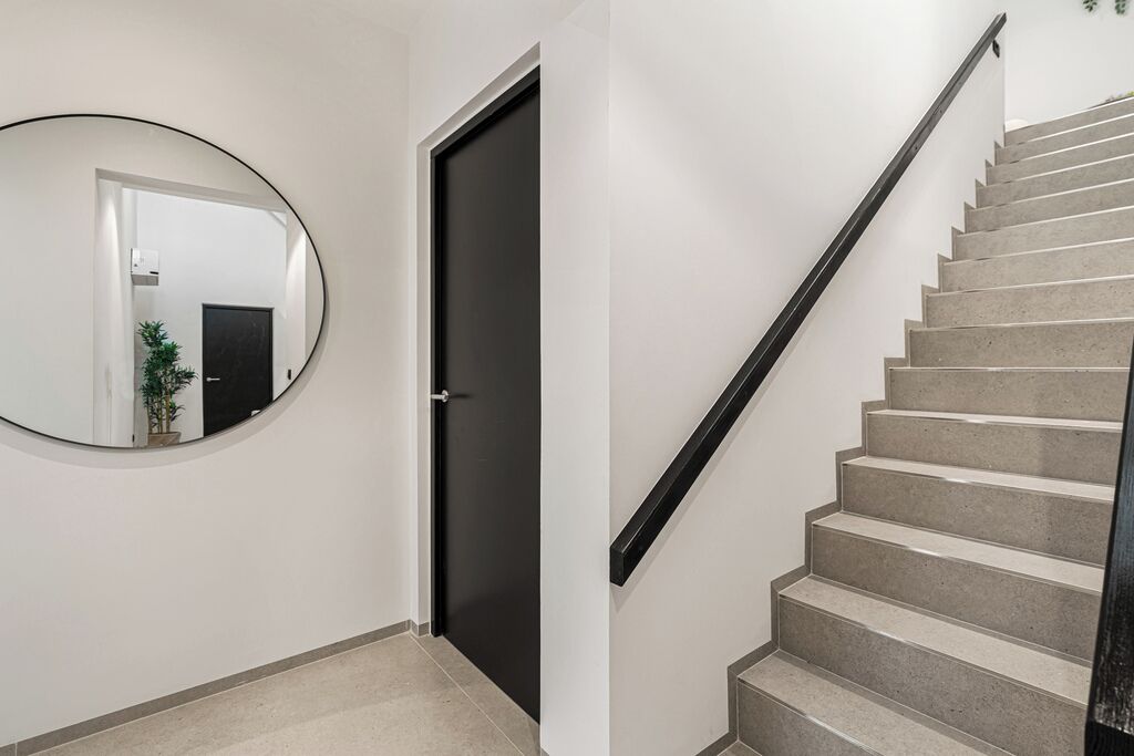 A staircase with a black handrail leading to a dark door.