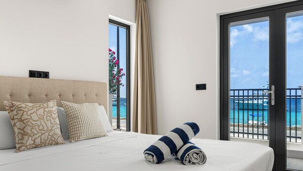 A hotel room with a bed, a view of the sea, and a balcony. - Oceanview 2-bedroom Apartment in Bonaire (Kralendijk)