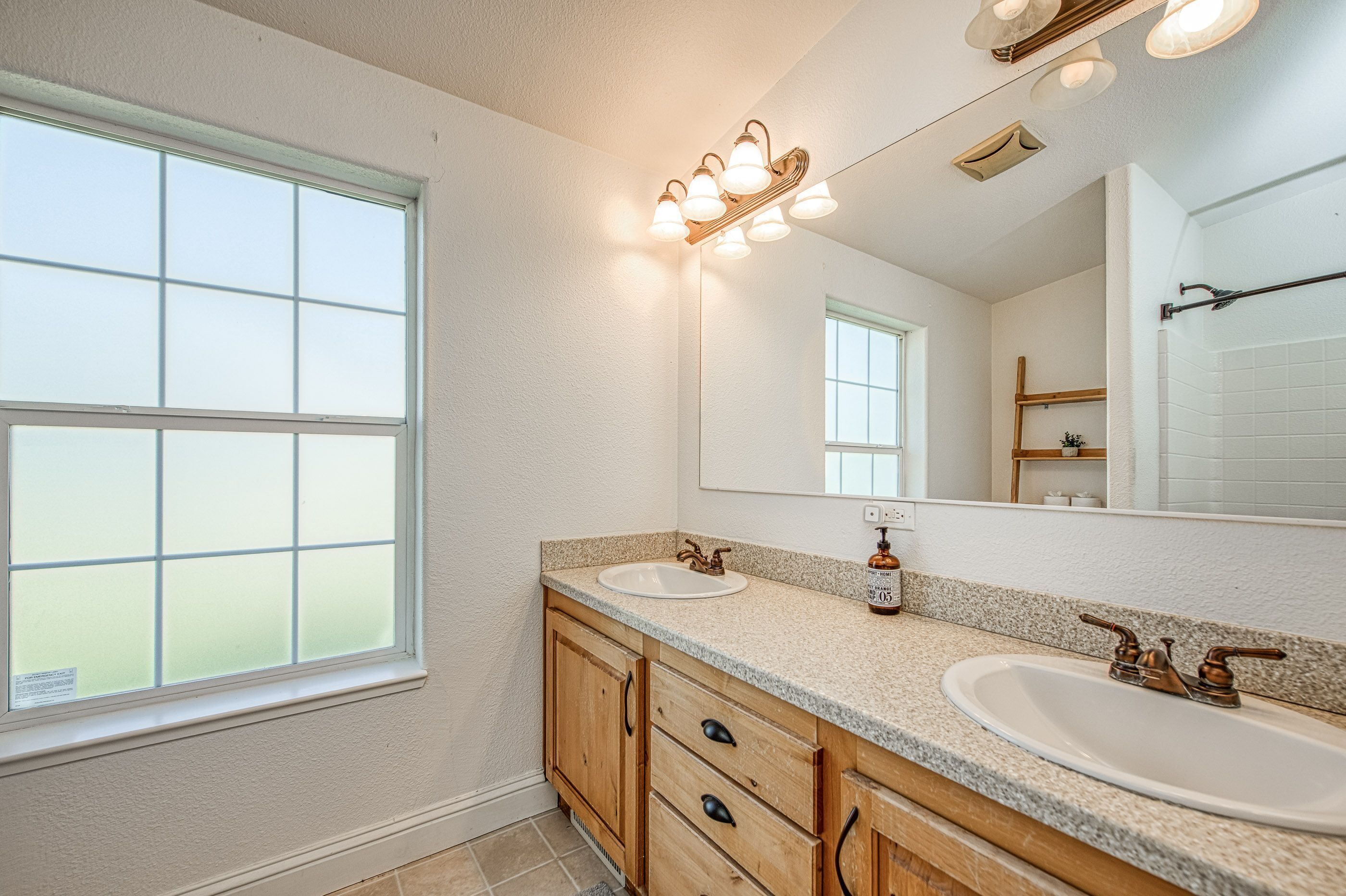 A bathroom with two sinks, a large mirror, and a window.