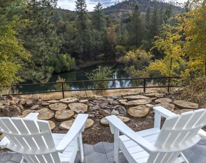 Two white Adirondack chairs facing a river with a forest backdrop. - Peaceful Lakeview Retreat Near Yosemite (Midpines)