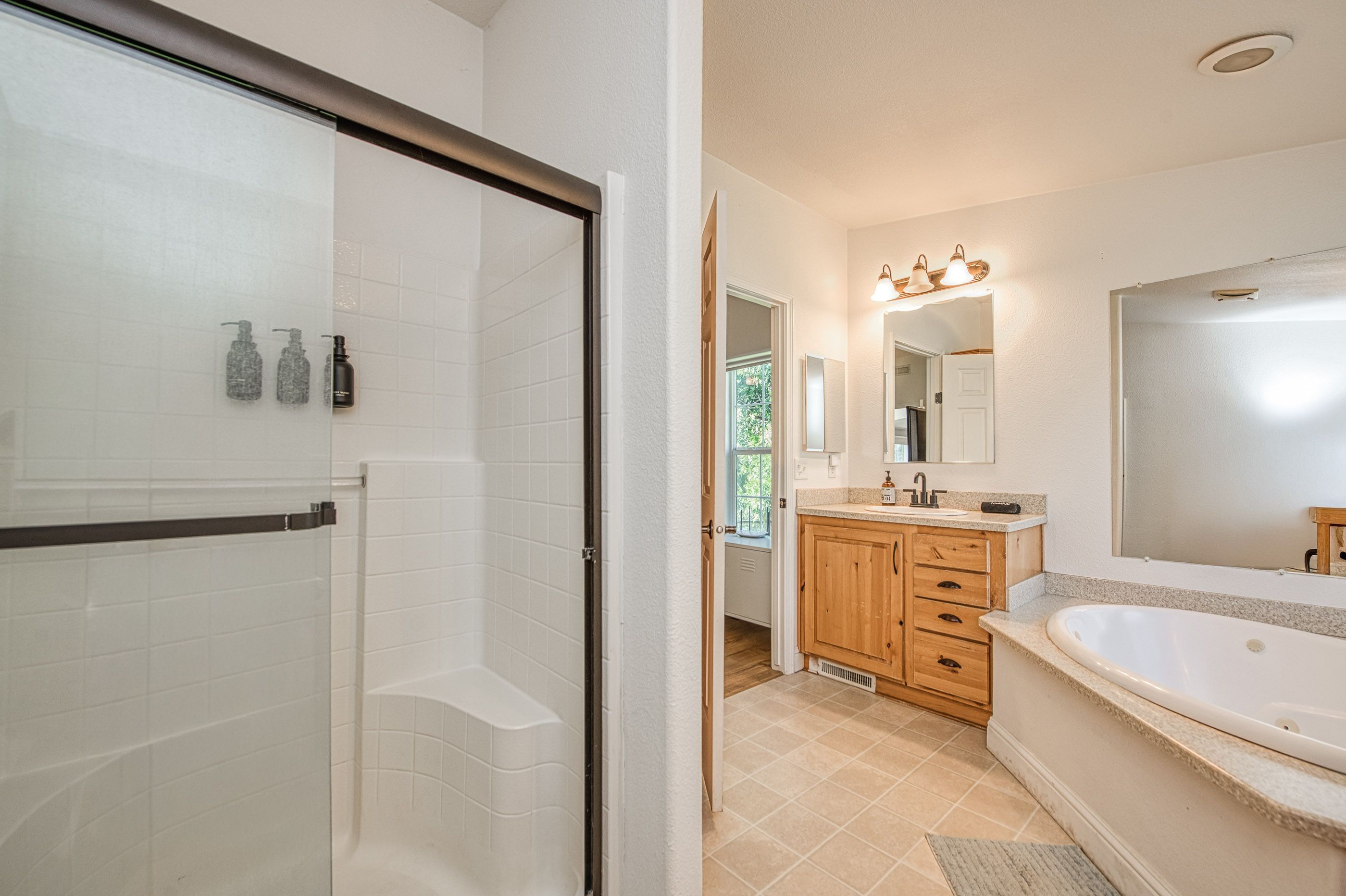 A modern bathroom with a glass shower enclosure, a freestanding bathtub, and wooden cabinetry.
