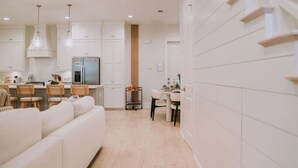 Una cocina moderna con armarios blancos, una isla central y un comedor con un sofá blanco.