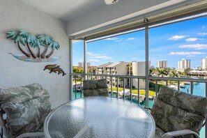 Enjoy morning coffee or evening drinks on the screened balcony overlooking the waterway. - Water Views, Beach Access, Pool, Pickleball, More (Fort Myers Beach)