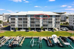 A multi-story hotel with a flat roof, balconies, and a marina with boats docked. - Water Views, Beach Access, Pool, Pickleball, More (Fort Myers Beach)