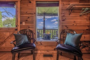 A wooden cabin with two chairs facing a table and a fire pit, a window with a view of trees, and a wooden ceiling. - Amazing views,  Dollywood, Gatlinburg, pigeon forge under 10miles, 3 kings,games (Sevierville)