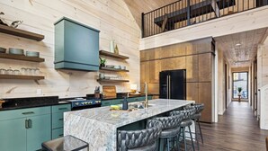 Una cocina moderna con una isla de mármol, taburetes de bar y un refrigerador negro.
