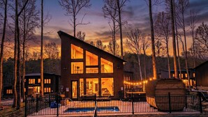 Una cabaña moderna de dos pisos con ventanas amplias, una piscina y una terraza.