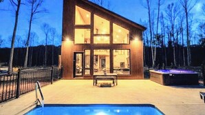 Un edificio moderno de dos pisos con amplios ventanales, una piscina y un jacuzzi.