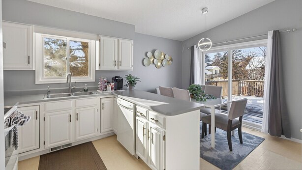 A modern kitchen with white cabinetry, a large window, and a dining area with a view of the outdoors. - Delightful 5-bedroom house with AC in Little Canada (Little Canada)