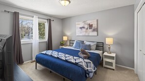 A bedroom with a bed, bedside tables, a ceiling light, a window with curtains, and a wall-mounted painting. - Delightful 5-bedroom house with AC in Little Canada (Little Canada)