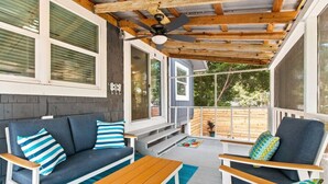 A covered outdoor seating area with a wooden ceiling, a sofa, a chair, and a table. - Walk to beach & trail-bikes, beach gear, porch (Palm Harbor)