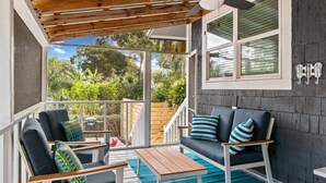 A covered outdoor seating area with a ceiling fan, wooden deck, and a view of the garden. - Walk to beach & trail-bikes, beach gear, porch (Palm Harbor)