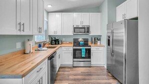 A modern kitchen with white cabinets, stainless steel appliances, and a wooden countertop. - Bike to trails, beach, parks - great for families! (Palm Harbor)